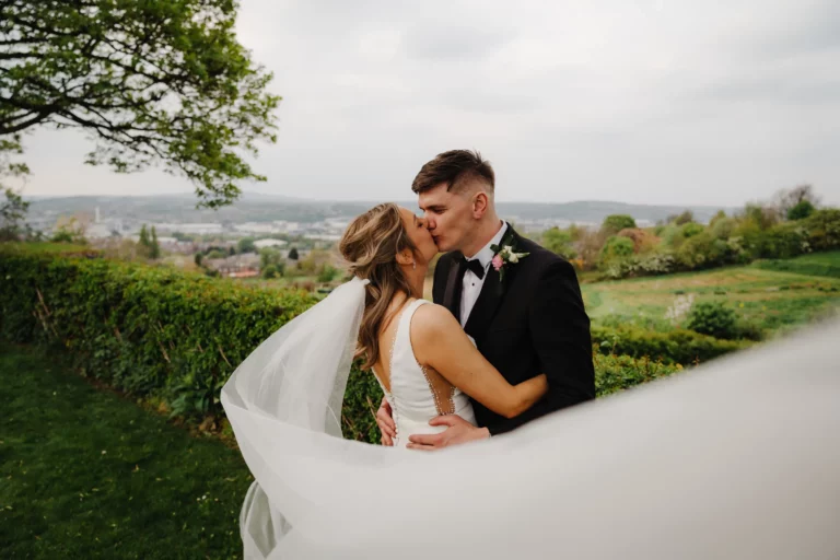 A man and woman snogging in front of bushes. Bethany Maeve Photography