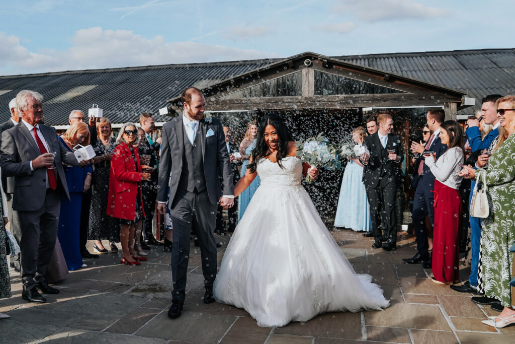 Bride and groom walking through wedding guests outdoors