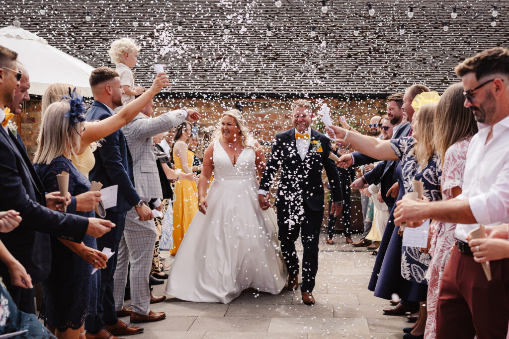 Newlywed couple celebrating with confetti outdoors at Donington Farm House