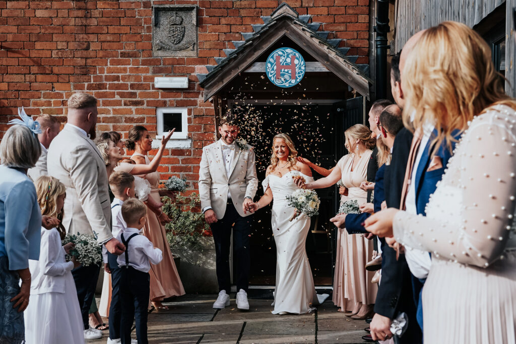 Newlywed couple exits church amid guests throwing confetti