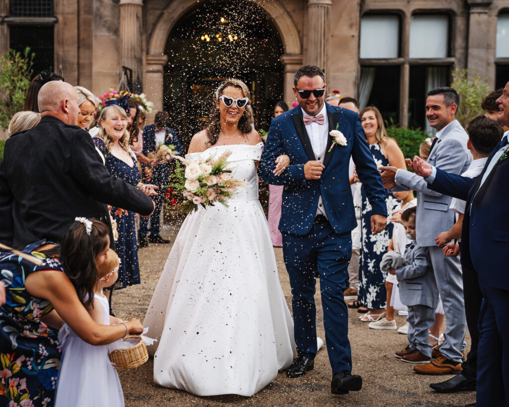 Bride and groom celebrating with guests throwing confetti
