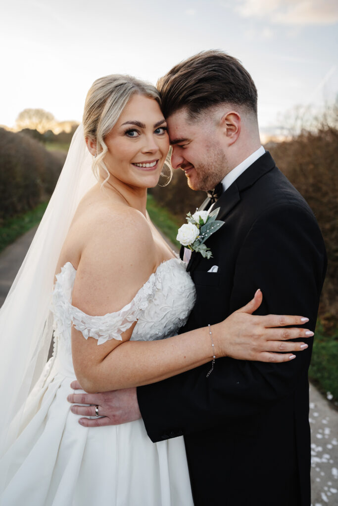 Smiling bride and groom embracing outdoors