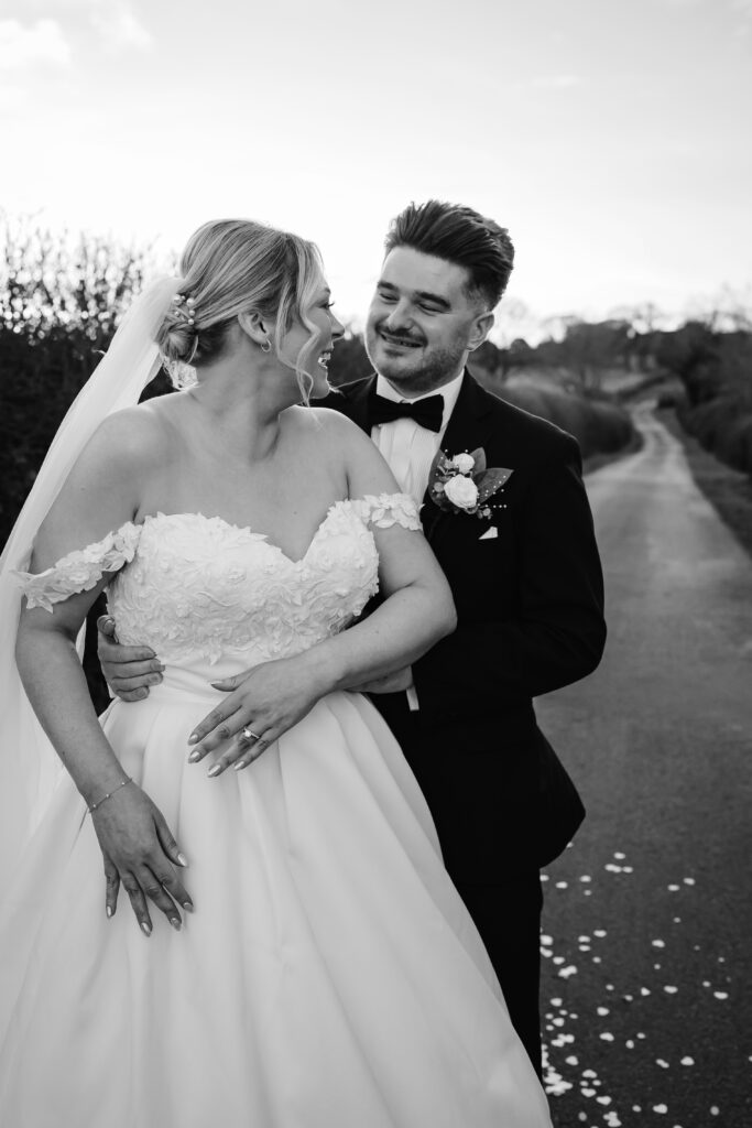 Bride and groom smiling on country road