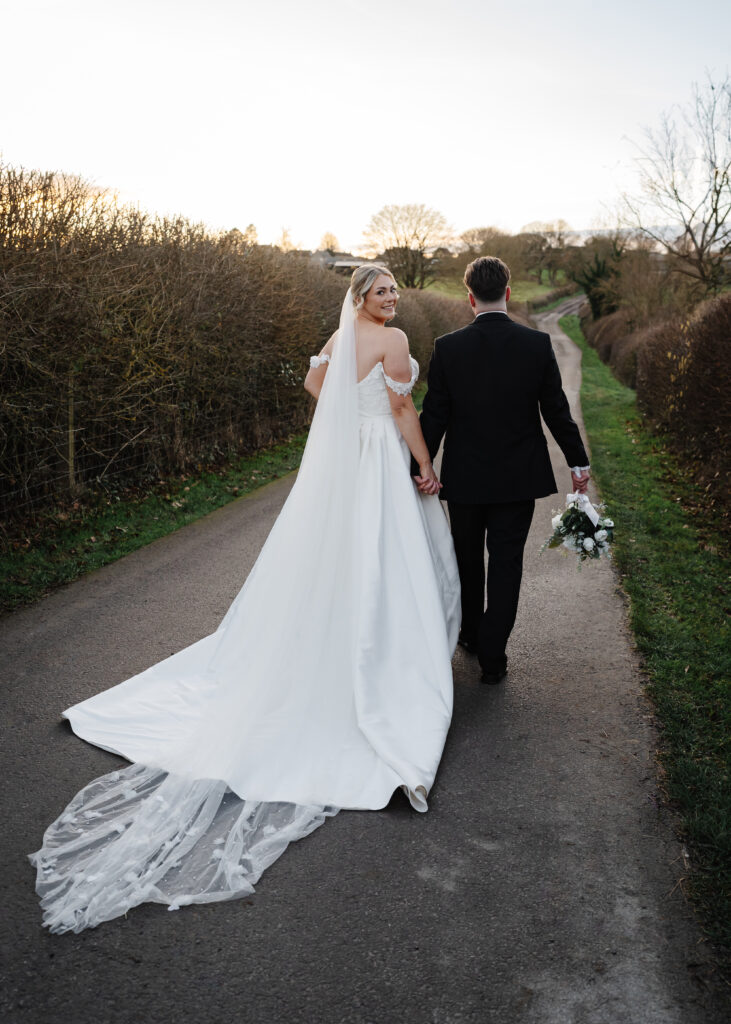 Bride and groom walking down countryside road